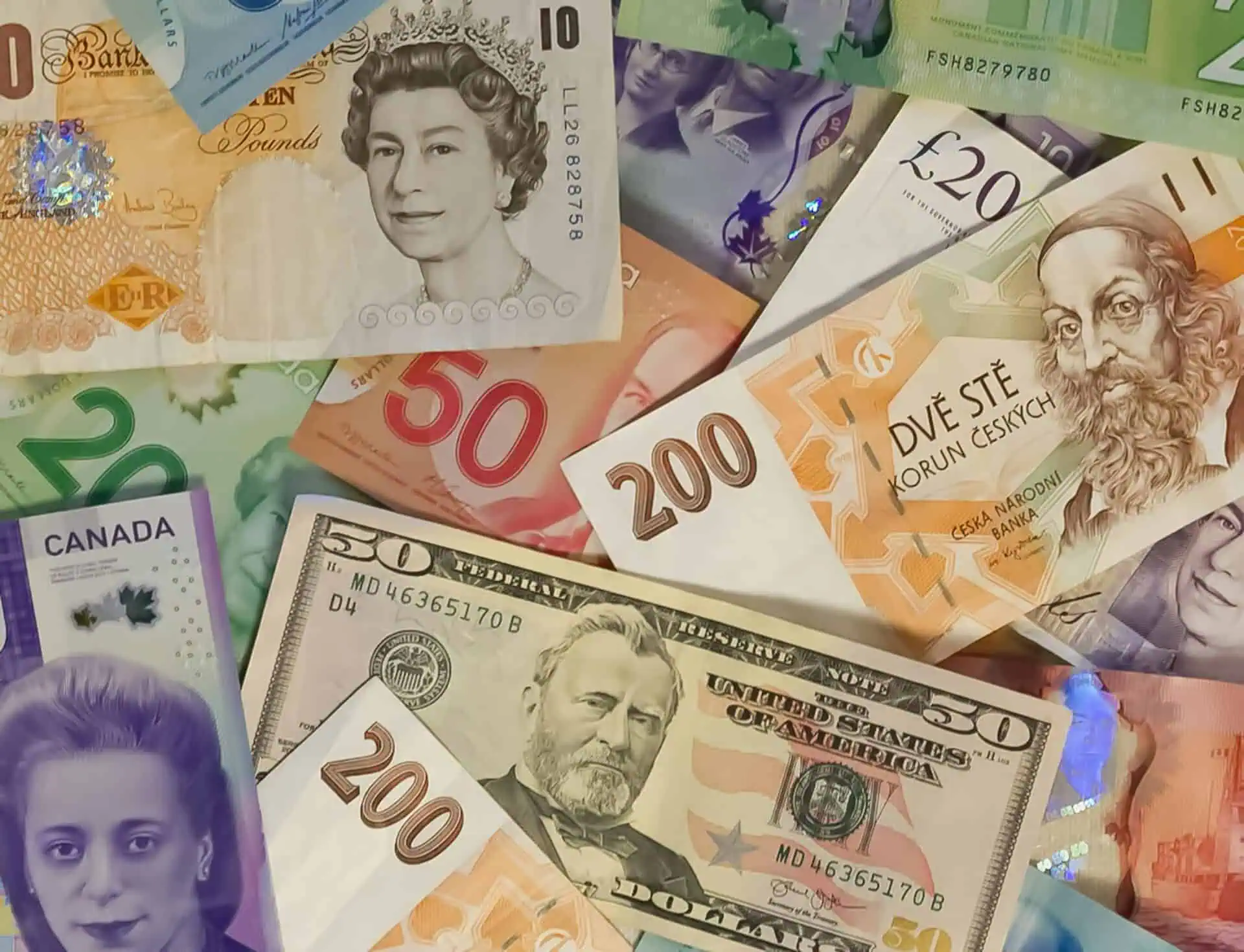 Een verscheidenheid aan kleurrijke bankbiljetten uit verschillende landen, ideaal voor wie geld wisselen of valuta omrekenen zoekt, waaronder Britse ponden, Amerikaanse dollars, Canadese dollars, Tsjechische kronen en eurobiljetten liggen verspreid in een overlappende opstelling.
